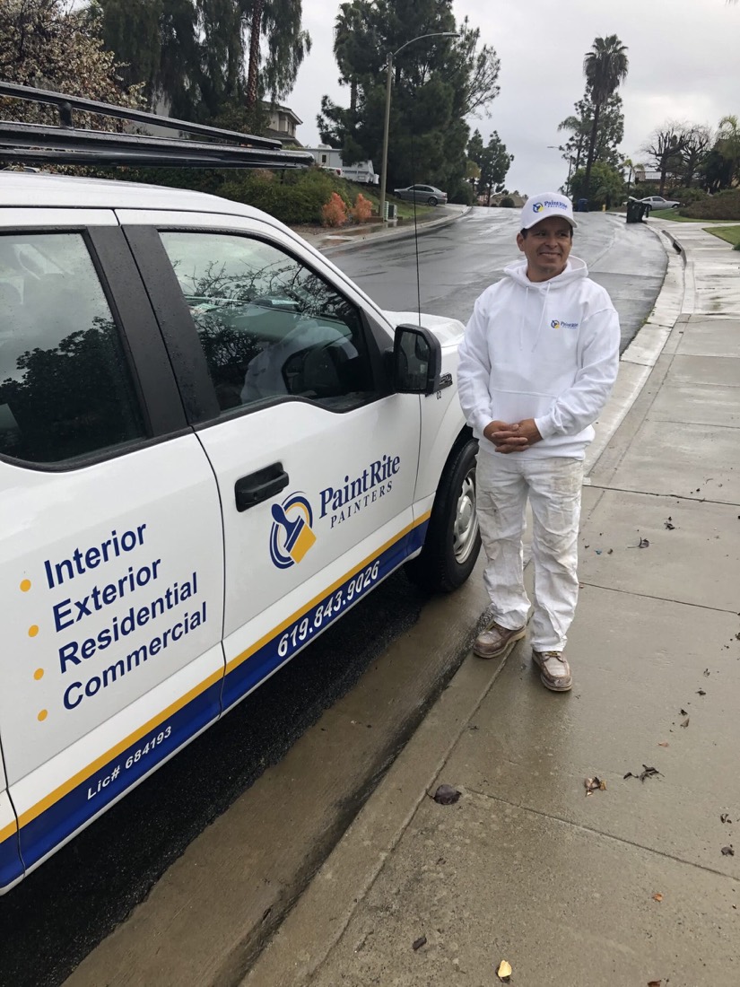 A PaintRite painter in company uniform beside a PaintRite truck